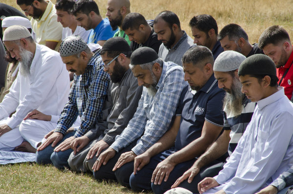 Homens muçulmanos ajoelhados fazendo sua prece.