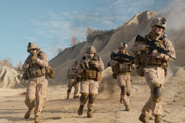 Esquadrão de soldados estadunidenses equipados, armados e correndo durante operação militar no deserto.