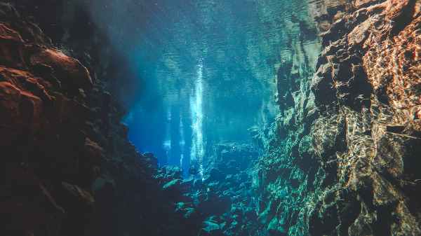Pessoas mergulhando na famosa fenda entre duas placas tectônicas chamada Silfra, na Islândia
