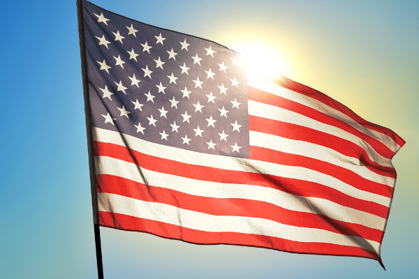 Bandeira dos Estados Unidos balançando ao vento em frente ao Sol.