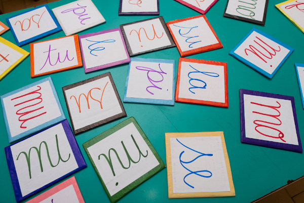 Cartões coloridos, com sílabas aleatórias escritas, sobre uma superfície plana de cor verde azulada.