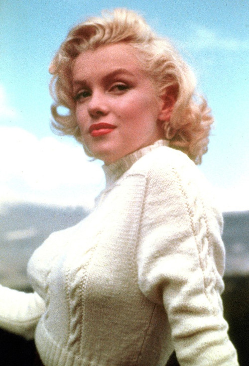 Marilyn Monroe séria com cabelos ondulados e blusa com gola rolê, em 1953.