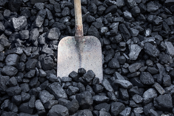 Pá enterrada em um monte de carvão mineral, que é considerado um recurso mineral.