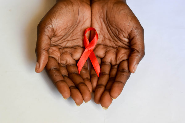 Mãos negras segurando laço vermelho, Dezembro Vermelho HIV, aids e ISTs