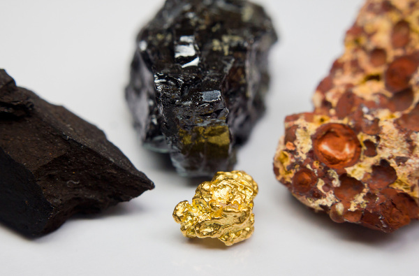 Recursos minerais sobre uma mesa: ouro, bauxita, carvão-preto e carvão-marrom.