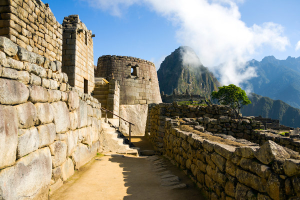 Construções rochosas em uma via, em Machu Picchu, com uma paisagem montanhosa ao fundo.