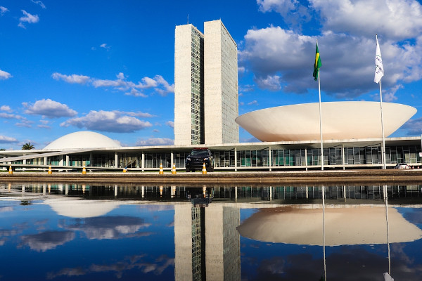 Sede do Congresso Nacional, em Brasília, com reflexo do prédio no espelho d’água à sua frente.