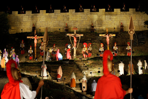 Soldados, três homens crucificados e figurantes em uma encenação da crucificação de Jesus, que ocorre na Sexta-Feira Santa.