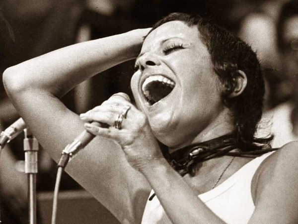 Vista aproximada do rosto de Elis Regina, uma das maiores cantoras do Brasil, cantando.