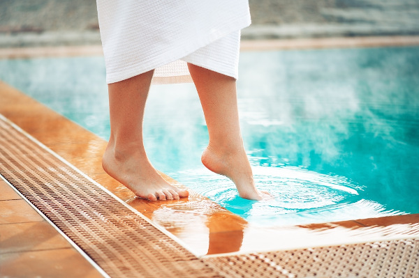 Pessoa tocando o pé na água de uma piscina, uma forma de perceber a sensação térmica.