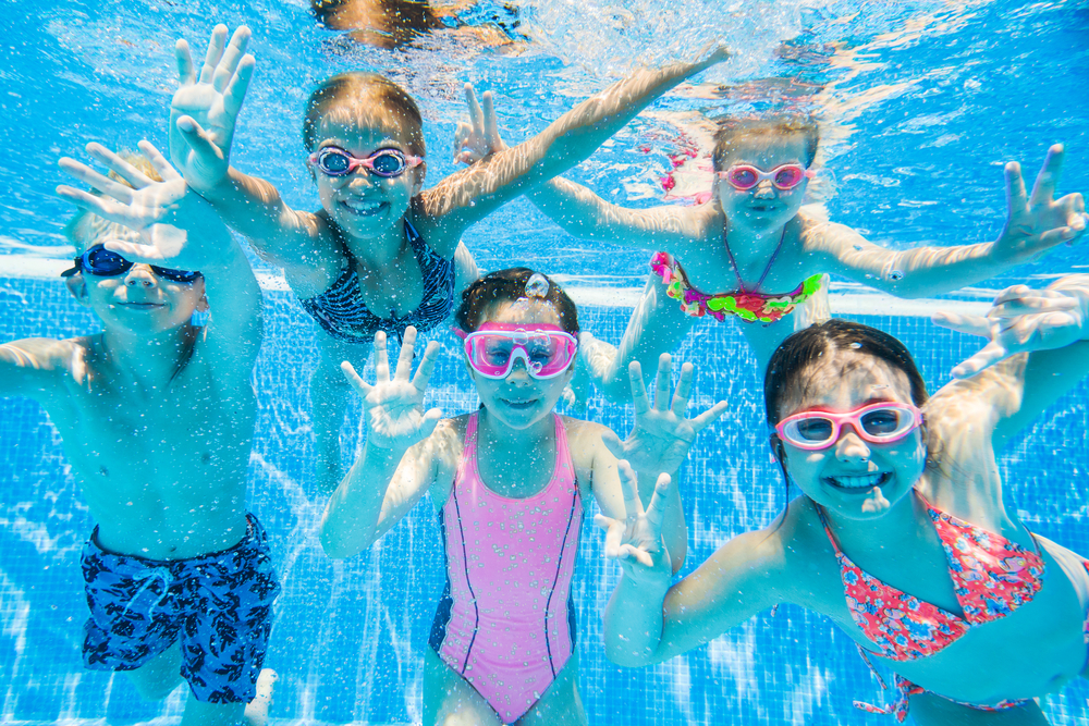 Crianças brincando na piscina em referência à colônia de férias.