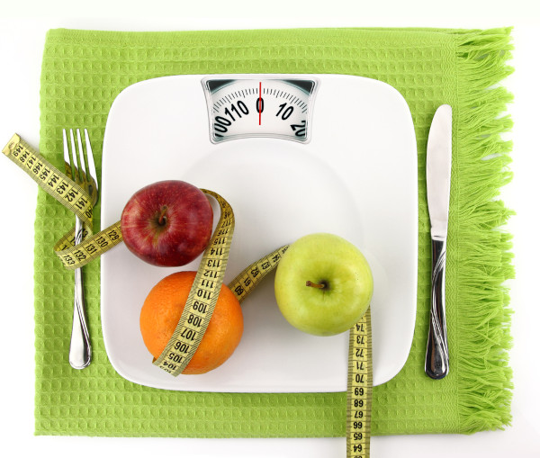 Frutas e fita métrica sobre uma balança em alusão ao terrorismo nutricional.