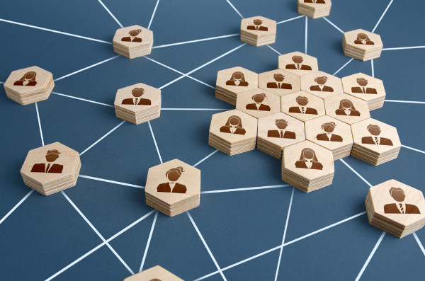 Pequenos hexágonos de madeira ligados por linhas e com a silhueta de pessoas desenhada neles em alusão às relações sociais.