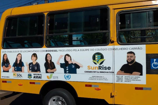 Na foto, ônibus escolar amarelo com foto das participantes do projeto de biodiesel