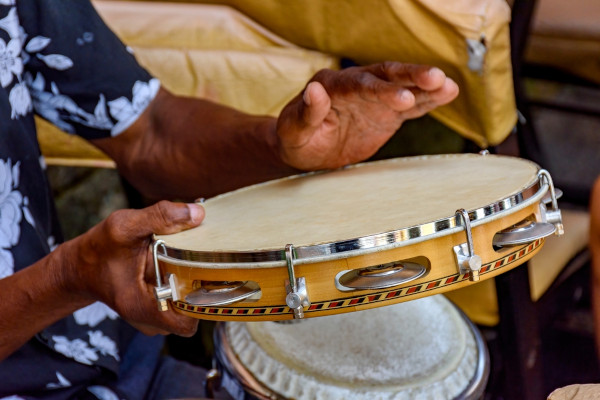 Homem tocando um pandeiro, um dos instrumentos do samba, ritmo musical que faz parte da cultura do Sudeste.
