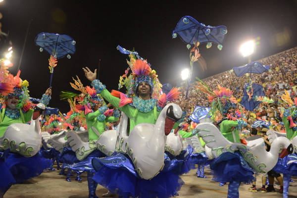 Membros de escola de samba desfilando no Carnaval, em texto sobre harmonia e evolução.
