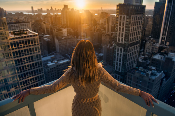 Executiva olhando a paisagem do topo de um edifício, exemplo da presença das mulheres no mercado de trabalho.