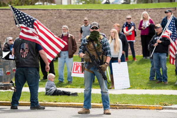 Membro de uma milícia norte-americana segurando arma próximo a outros manifestantes.