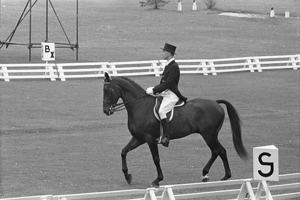 Foto em preto e branco mostra Reiner Klimke montado em um cavalo em um campo de hipismo.
