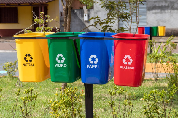 Quatro lixeiras com as cores da coleta seletiva usada na reciclagem.