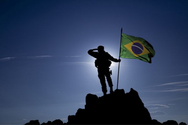 Soldado segura a bandeira do Brasil no topo de um monte