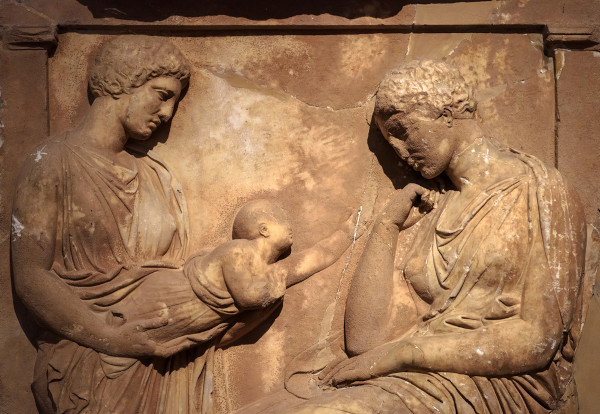 Escultura grega representando duas mulheres, uma delas segurando um bebê.