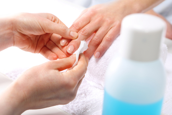 Manicure limpando o esmalte das unhas de uma cliente com acetona, uma das principais aplicações das cetonas.