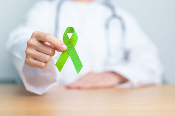 Médico segurando uma fita verde-claro, a cor escolhida para campanha de conscientização sobre os linfomas.