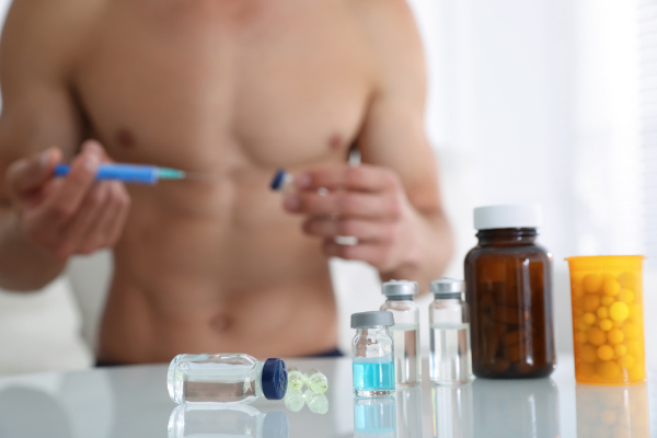 Homem musculoso preparando seringa, uma alusão ao doping.