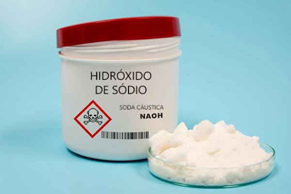 Recipiente e fragmentos brancos de soda cáustica, com o nome e a fórmula do hidróxido de sódio.