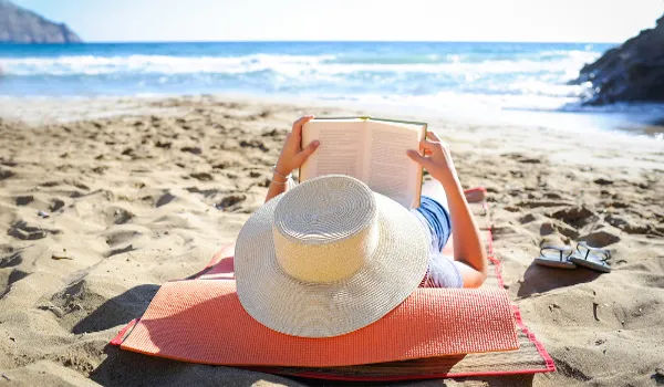 Jovem lendo um livro na praia