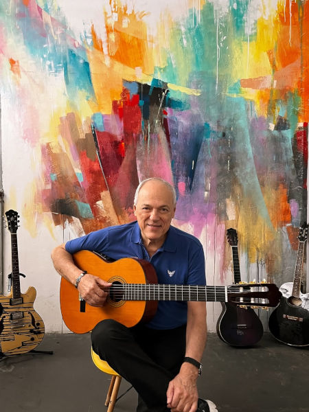 Fotografia de Toquinho à frente de uma aquarela.