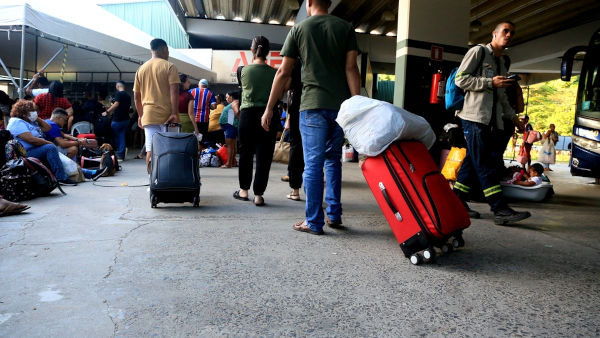 Pessoas segurando malas em rodoviária de Salvador, em referência à migração interna. [imagem_principal]