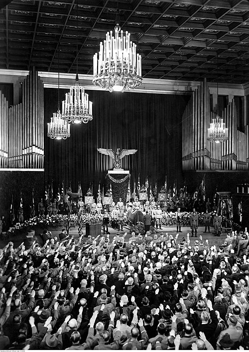Adolf Hitler presta continência no funeral de Adolf Wagner no salão de congressos do Deutsches Museum de Munique, em 1944.