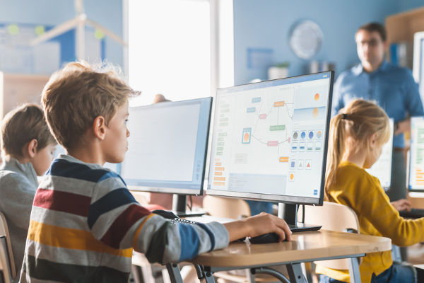 Crianças em frente a computadores em sala de aula