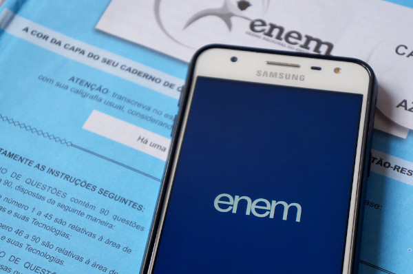 Caderno de provas do Enem, caneta preta e smartphone