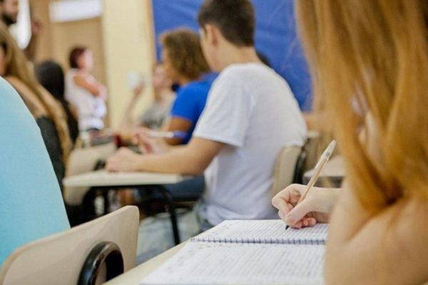 Estudante branca em frente ao computador, texto Fies 2024 Estados com mais vagas
