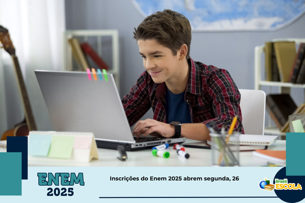 estudante morena com óculos sorrindo em frente a notebook