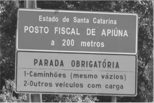 Placa de trânsito com o texto: “Estado de Santa Catarina. Posto fiscal de Apiúna a 200 metros”.