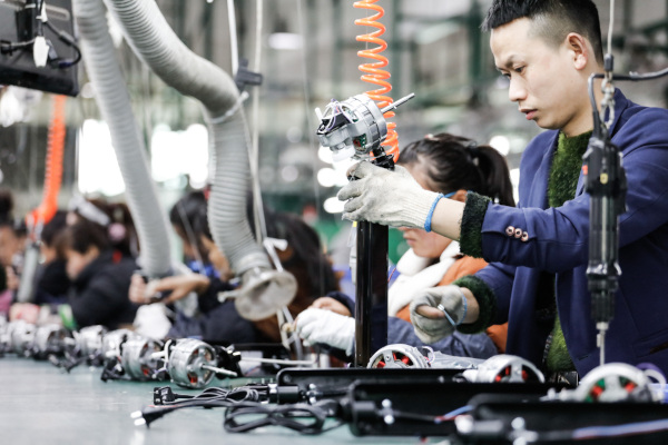 Operários chineses trabalhando em uma fábrica, em referência à divisão social do trabalho.