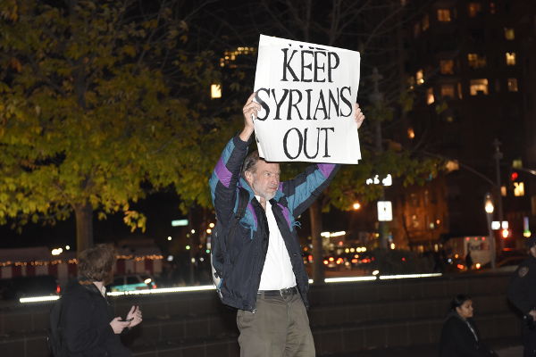 Homem segurando cartaz com mensagem xenófoba nos EUA. No cartaz, está escrito: “mantenha os sírios fora” (dos EUA).