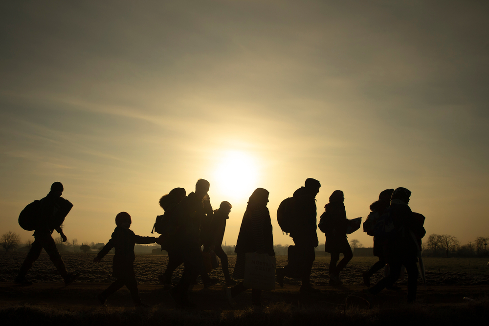 Sombra de pessoas refugiadas caminhando em campo aberto