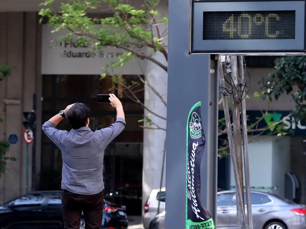 Homem tirando foto de termômetro na rua 