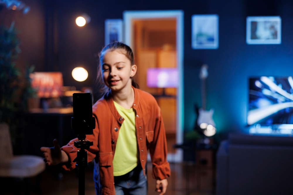 Criança gravando com celular, na sala